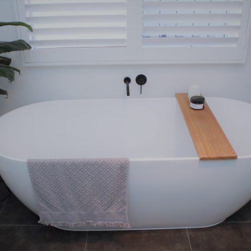 white bath with caddy and towel and matte black tap